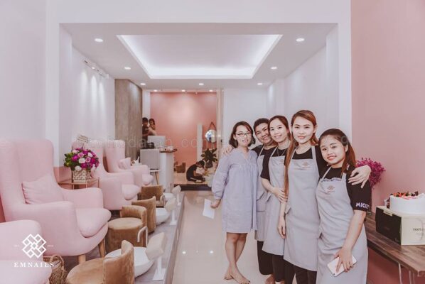 nhân viên nail mặc tạp dề in logo, tông màu đồng bộ với tiệm